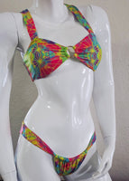 Mannequin wearing a colorful tie-dye bikini with a plain background