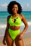 Woman in a bright green bikini standing on a beach with ocean in the background